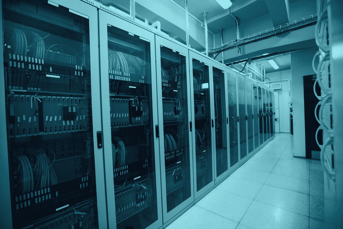 An aisle of server racks under a lit ceiling
